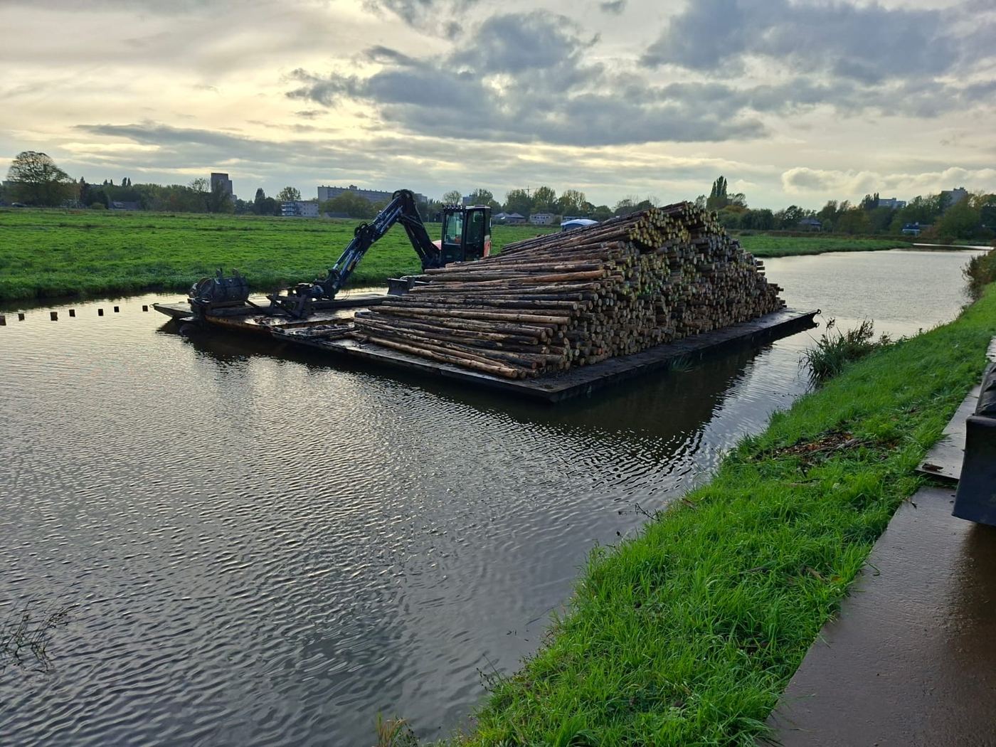 Ponton vol houten palen wordt over het water aangevoerd