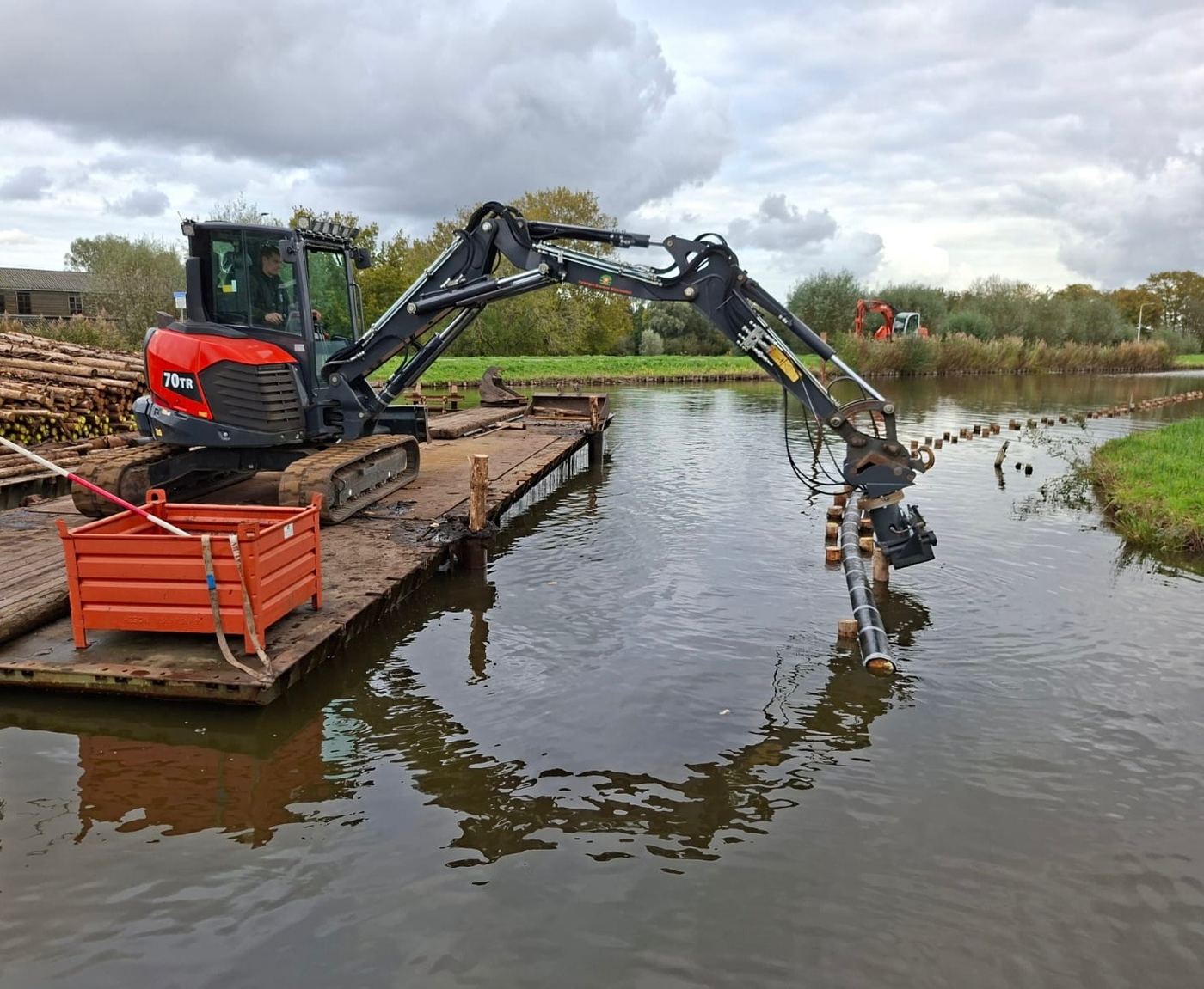 Graafmachine op een ponton plaatst palen voor een beschoeiing