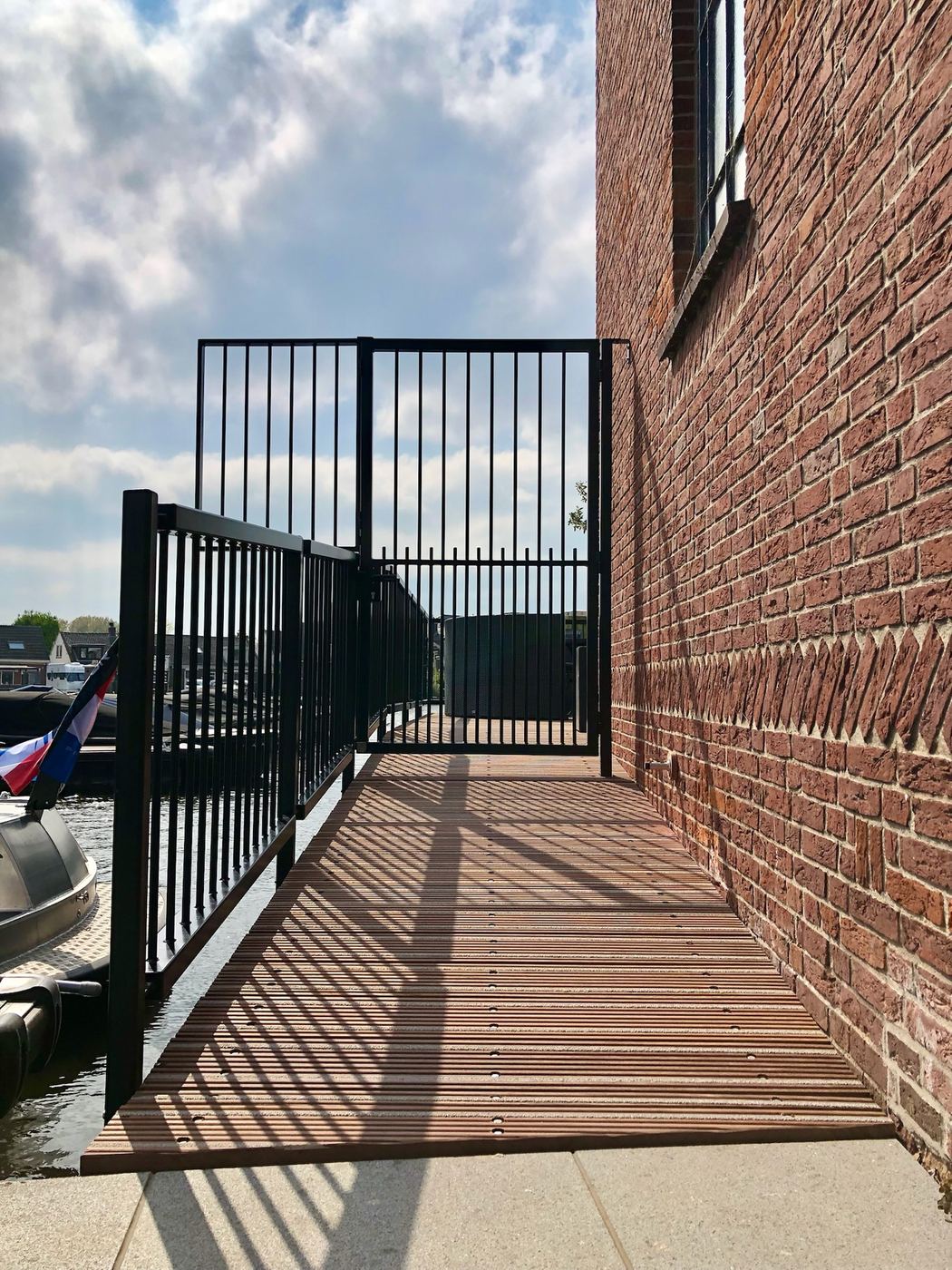Stalen hekwerk met poort op een houten terras